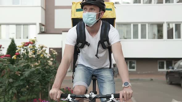 Food delivery service during the quarantine period on a bicycle in a yellow thermo backpack.