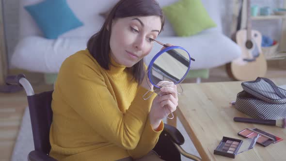 Portrait of a Young Disabled Woman in a Wheelchair Doing Makeup