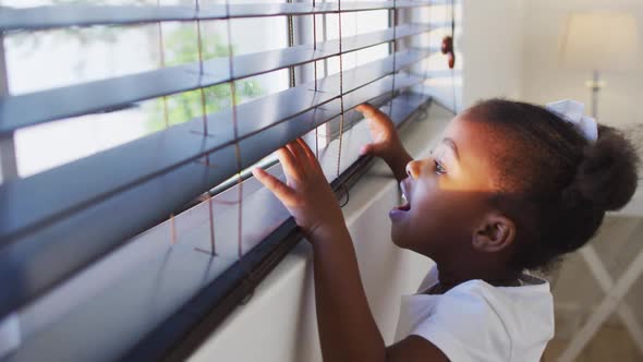 African american girl looking out the window at home