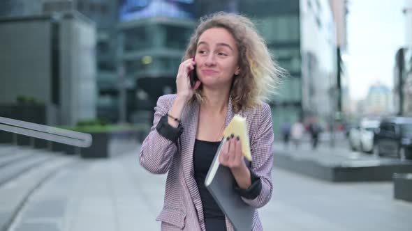 A woman, office worker goes about her business and eats a sandwich on the go