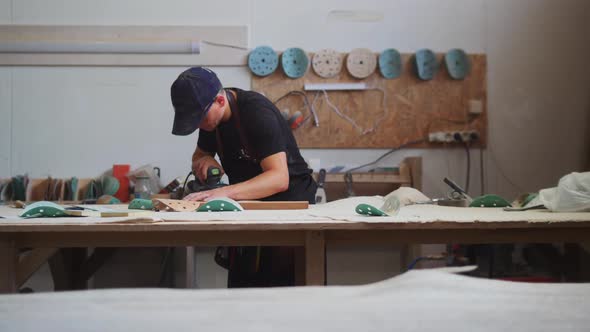 Carpentry Works  Man Worker in Protective Glasses Grinding the Angles of a Wooden Detail