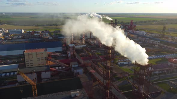 Aerial shot. White smoke comes from the chimneys of an industrial plant.