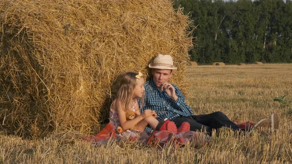 Little Girl with Father Sitting Near a Haystack