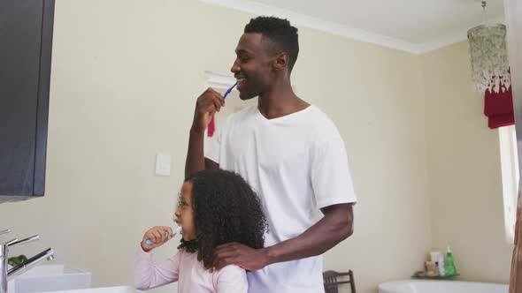 African american father and daughter brushing their teeth