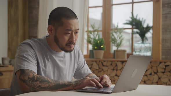 A Bunch of Various Facial Expressions By a Tattoed Asian Man in Front of His Laptop