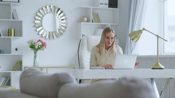 Young attractive woman holding video conference remotely from white room at home