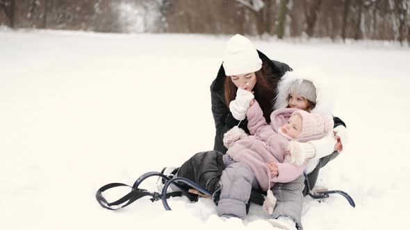 Mother Having Fun Sledding with Kids in Winter Forest