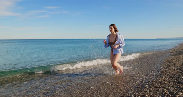 girl in shirt and bikini runs on the beach