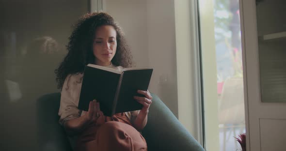 Mixed race woman reading by the window