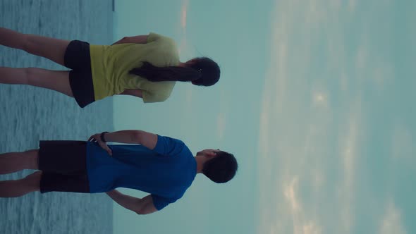 Vertical shot: Attractive sporty young fitness couple wearing sportswear working out outdoors.