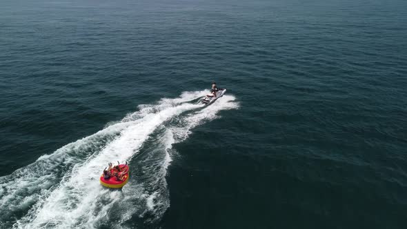 Happy People are Going to Swim on an Air Mattress Behind a Jet Ski