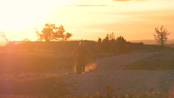 Young male fatbiking in Lapland with an electric fatbike and beautiful midnight sun behind him.