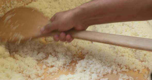A Chef Mixing A Freshly Cooked Japanese Sushi Rice In A Wooden Sushi Rice Bowl To Cool Down. - close