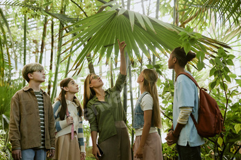 Tour Guide And Teenagers In Botanical Garden Glasshouse