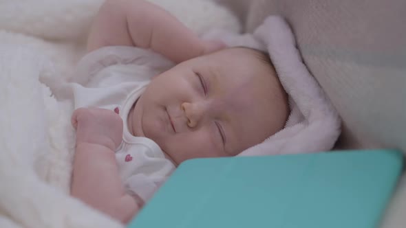 Charming Carefree Innocent Baby Girl Waking Up in Bed with Tablet Lying Aside