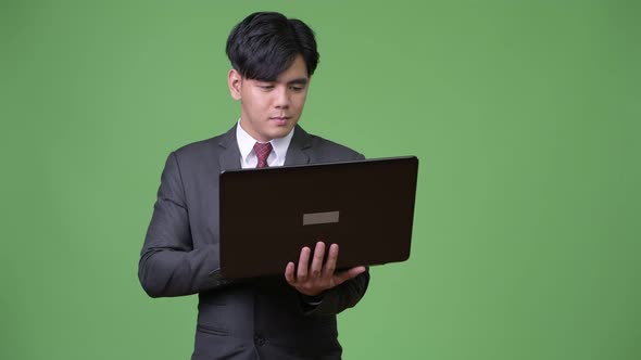 Young Handsome Asian Businessman Using Laptop