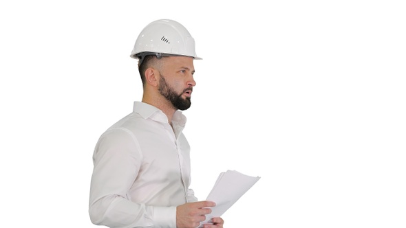 Male Engineer Walking in A Hard Hat Looking at Documents