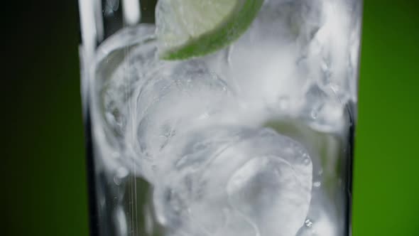 Ice Cubes Fall to the Highbowl Glass in Slow Motion Making the Isolated Cocktail on the Background