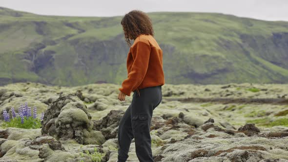 Woman Hiking Over Moss Covered Rocks In Landscape