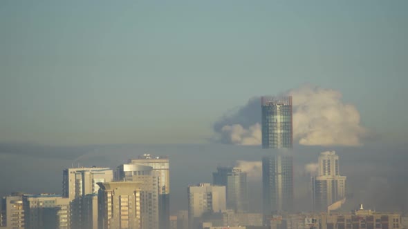 City Pipes Emit Steam Into the Atmosphere Against the City Skyline 4