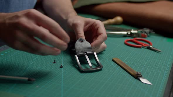 Craftsman Getting Pieces of Disassembled Leather Belt Together Indoors