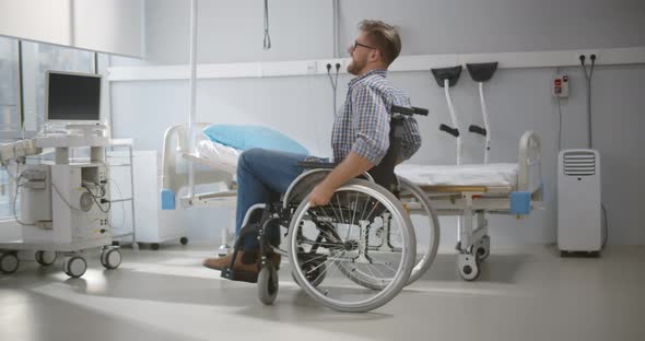 Happy Young Man Swirling Around in Wheelchair at Hospital Ward