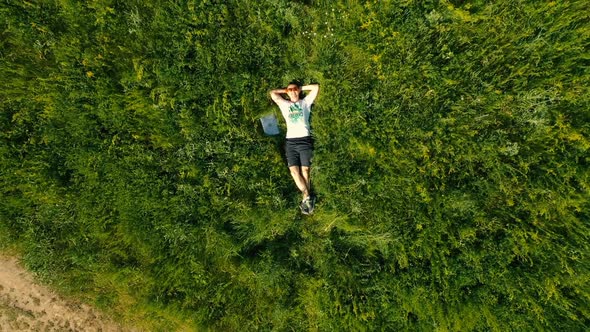 Man Freelancer Lying Down on Grass with Laptop. Aerial Drone Footage Top View.