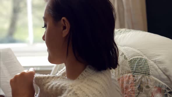 Beautiful woman reading novel in bedroom