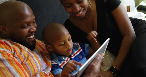 Parents and son using digital tablet on bed at home 4k