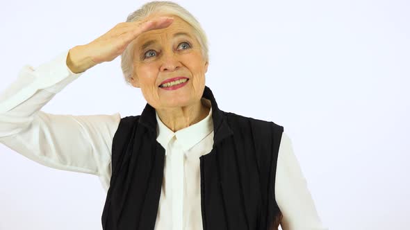 An Elderly Woman Protects Her Eyes from The Sun and Looks Into Distance with A Smile