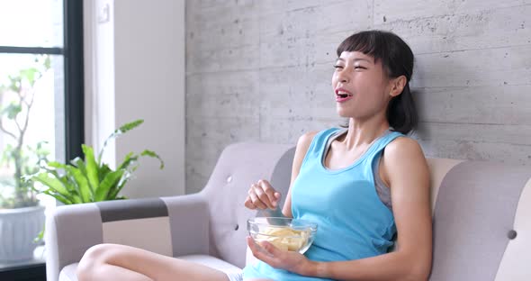 Woman watching comedy at home with eating snack