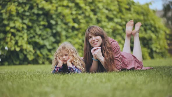 A Mother and Her Daughter Lie on the Grass in the Garden