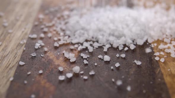 Spa sea salt falling on a rustic wooden surface