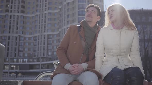 Portrait of Attractive Cuople Sitting at the City Street Talking and Smiling. The Couple Chatting