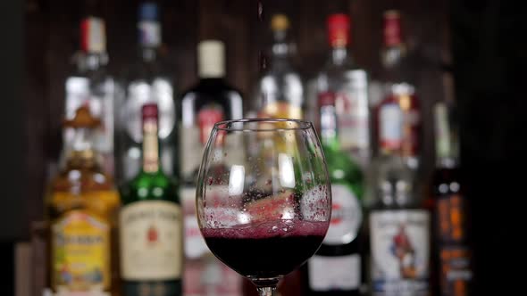 Closeup of a Bartender Pouring Red Wine From a Bottle Into a Glass in a Bar