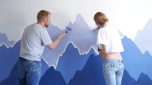 husband with pregnant wife paint mountains in nursery