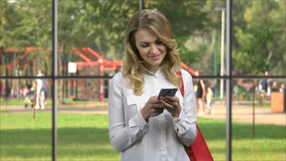 Happy Young Woman Typing Message on Her Smartphone