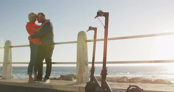 Senior couple embracing each other alongside beach