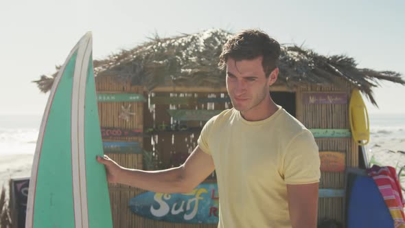 Caucasian man holding his surfboard