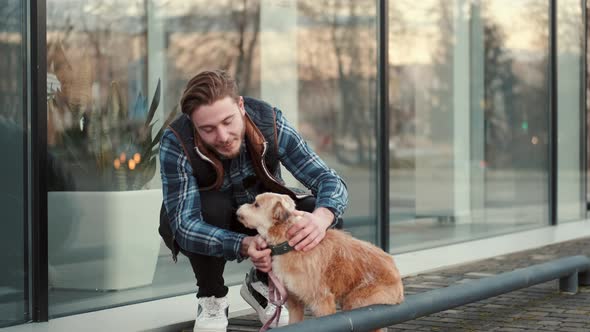 Young Man Sitting with Lovely Dog Outside Near Glass Building
