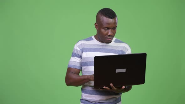 Young African Man Thinking While Using Laptop