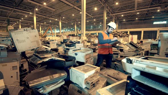 Discarded Office Machines with a Male Expert Inspecting Them