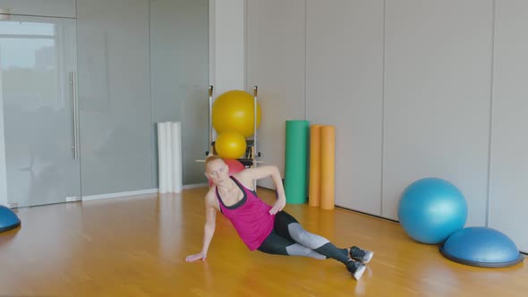 Wide Shot Portrait of Professional Trainer Exercising in Side Plank Position. Sportive Caucasian