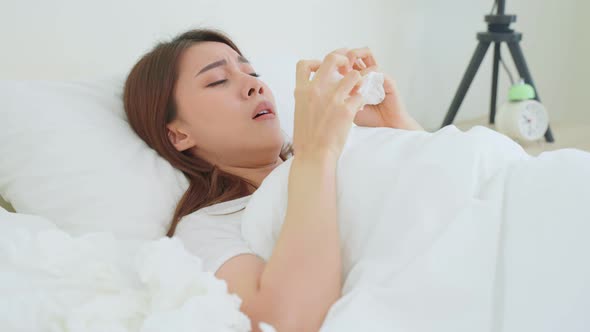 Asian sick woman wake up from sleep in the morning and sneezing on bed.