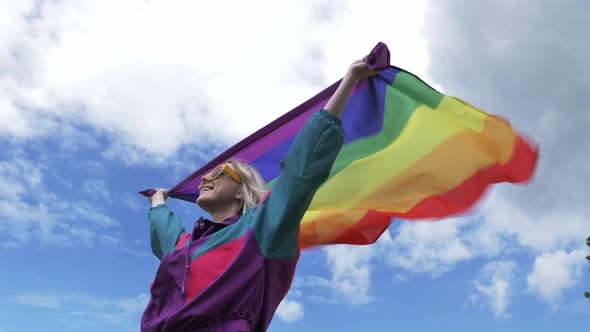 Female with LGBT rainbow flag on yellow rapeseed field in spring