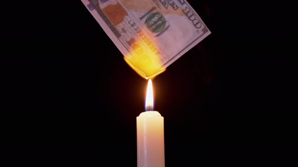 Burning 100 Dollar Bill Over a Smoky Candle Flame on a Black Background