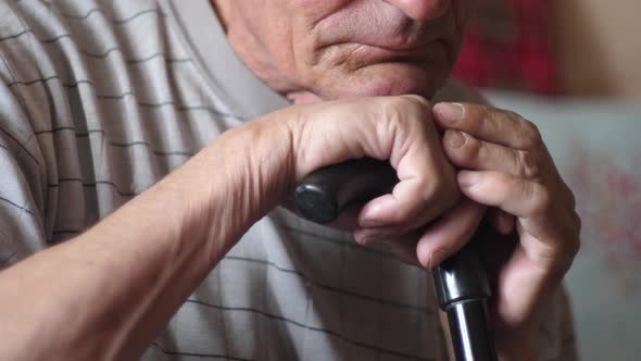 Close-up portrait of a serious sad caucasian pensioner 70-80 years old feathered sitting on a walkin