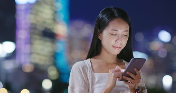 Woman look at mobile phone in city at night