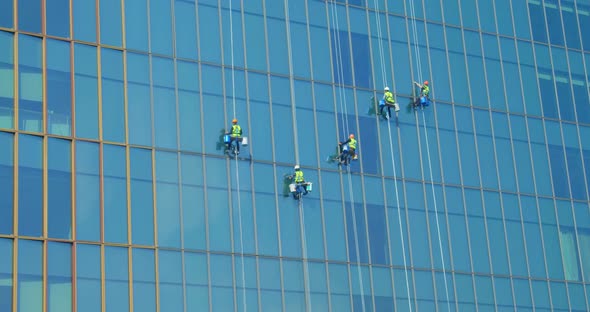 Five Men Workers in Red and Yellow Work Clothes Cleaning the Exterior Windows of a Business