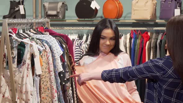 Female Friends Enjoying Shopping for Dresses Together at Clothing Boutique